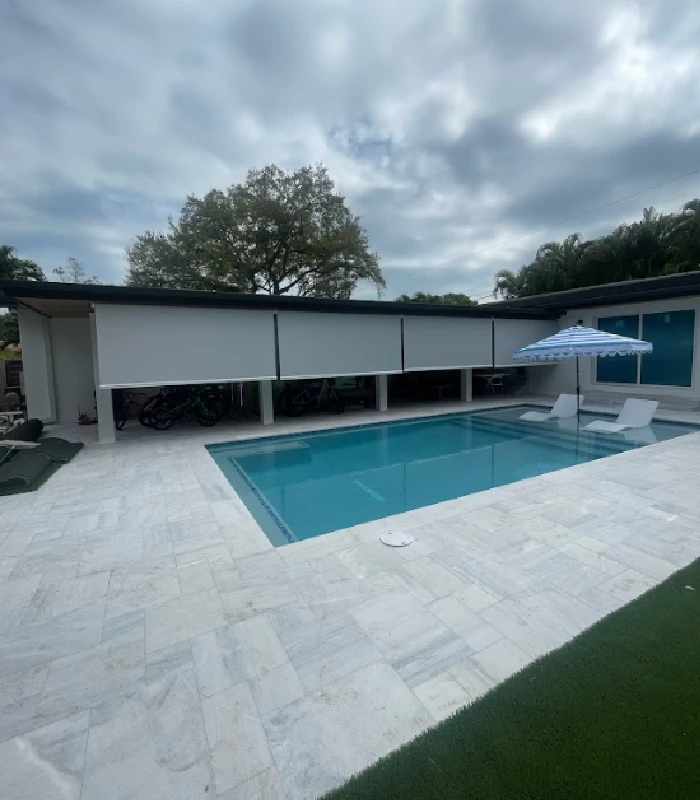 Outdoor motorized blinds installed by a modern pool area