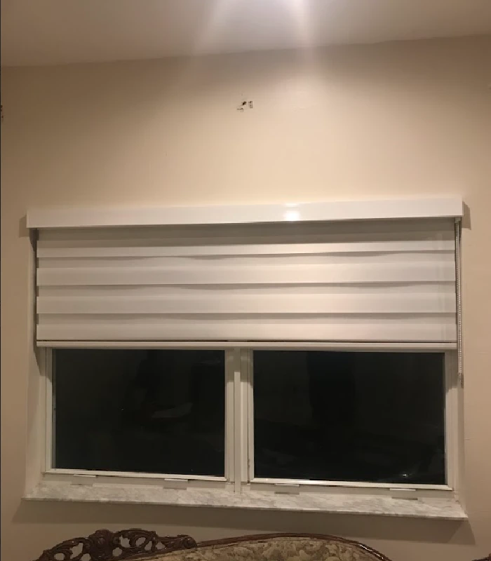 White roman blinds covering a double window at night