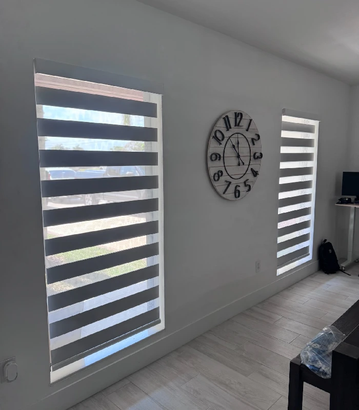 Tall zebra blinds filtering light beside a wall clock