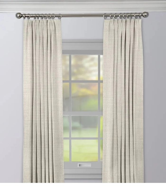 Full height drapes mounted inside a bedroom window frame with decorative curtains on each side, providing privacy and natural light control.