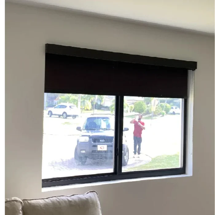Window with motorized blackout shades partially lowered for room darkening.
