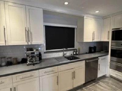 A wide view of a modern kitchen featuring a black blackout shade that provides full light control and privacy above the sink area.